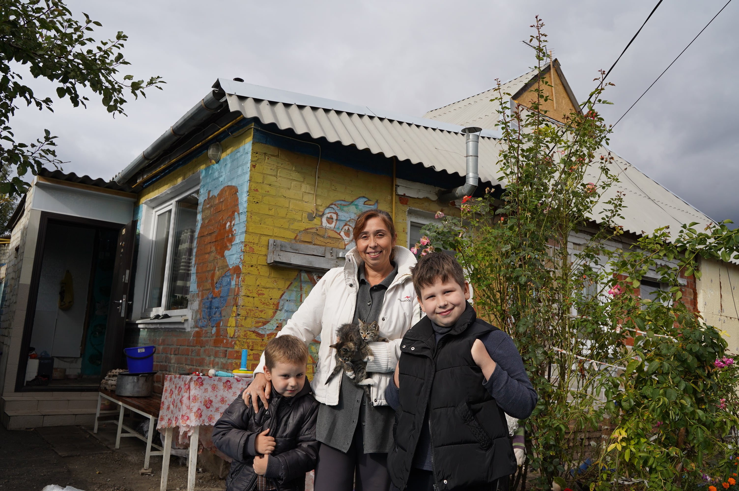 Nataliia and her children in front of their house which UNHCR helped repair