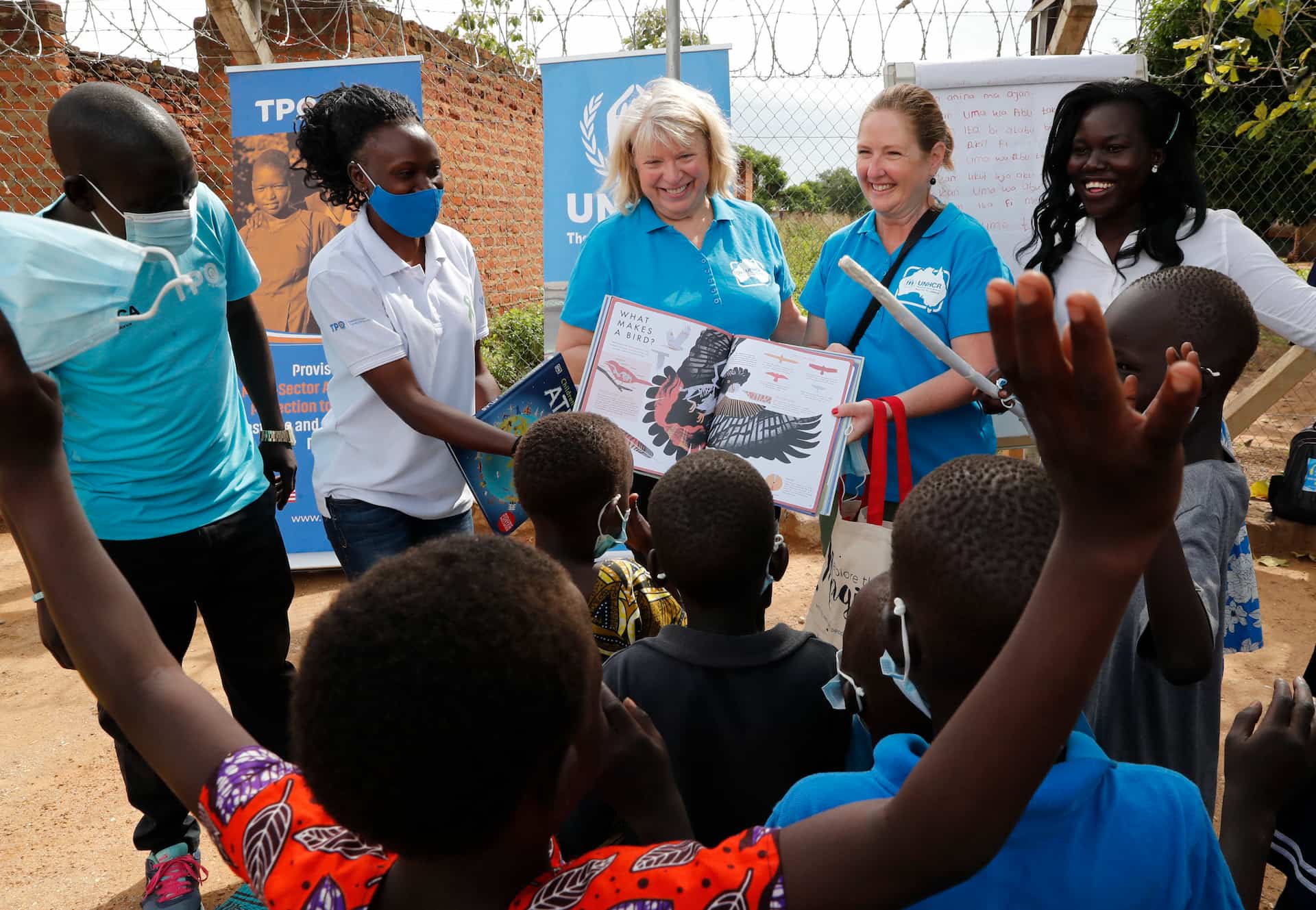 Naomi Steer and Elizabth Grady read a book to Ugandan children