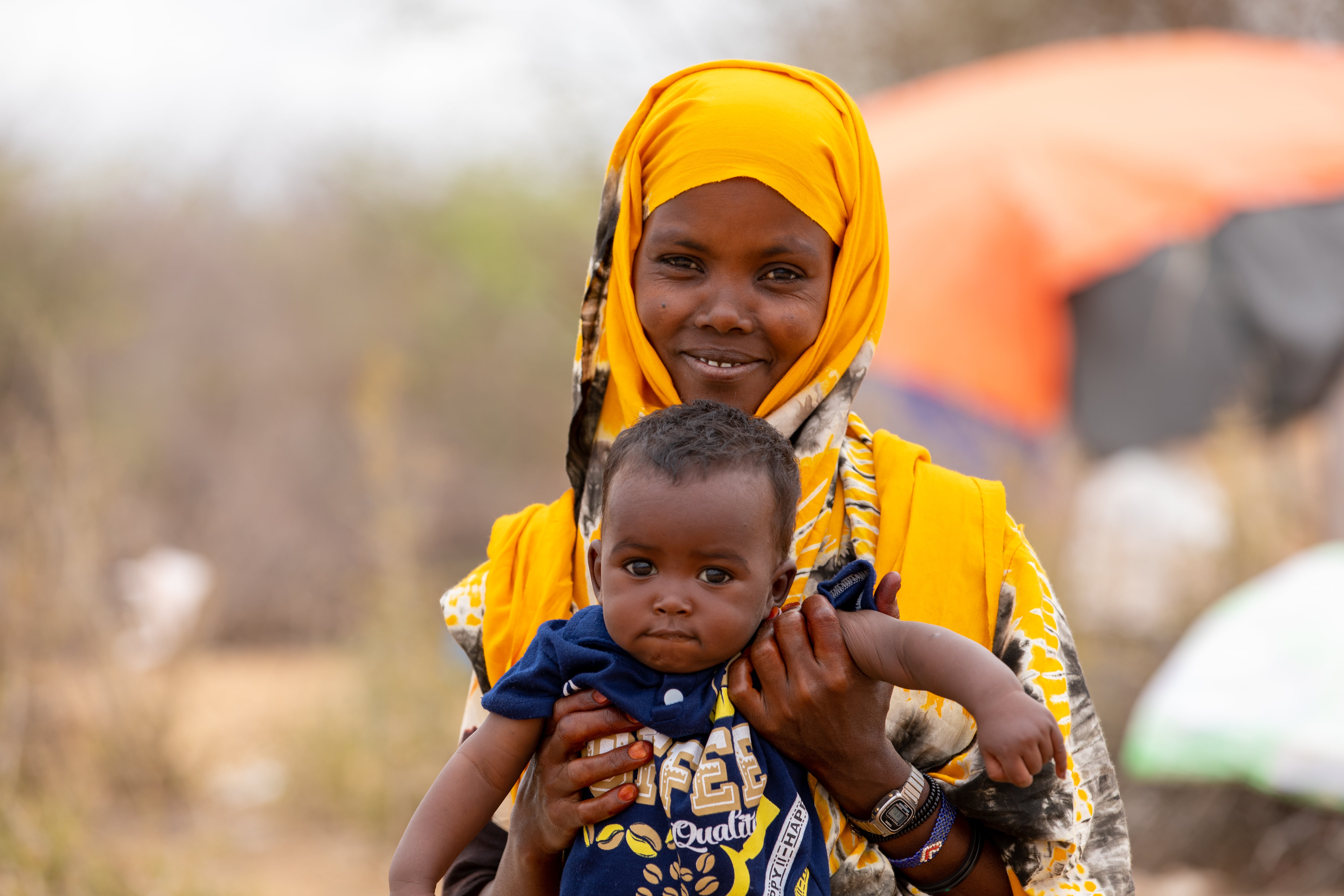 Abay Osman, 32-year-old mother of 6 holds her youngest son Hamza, 7 months outside their shelter in Dadaab