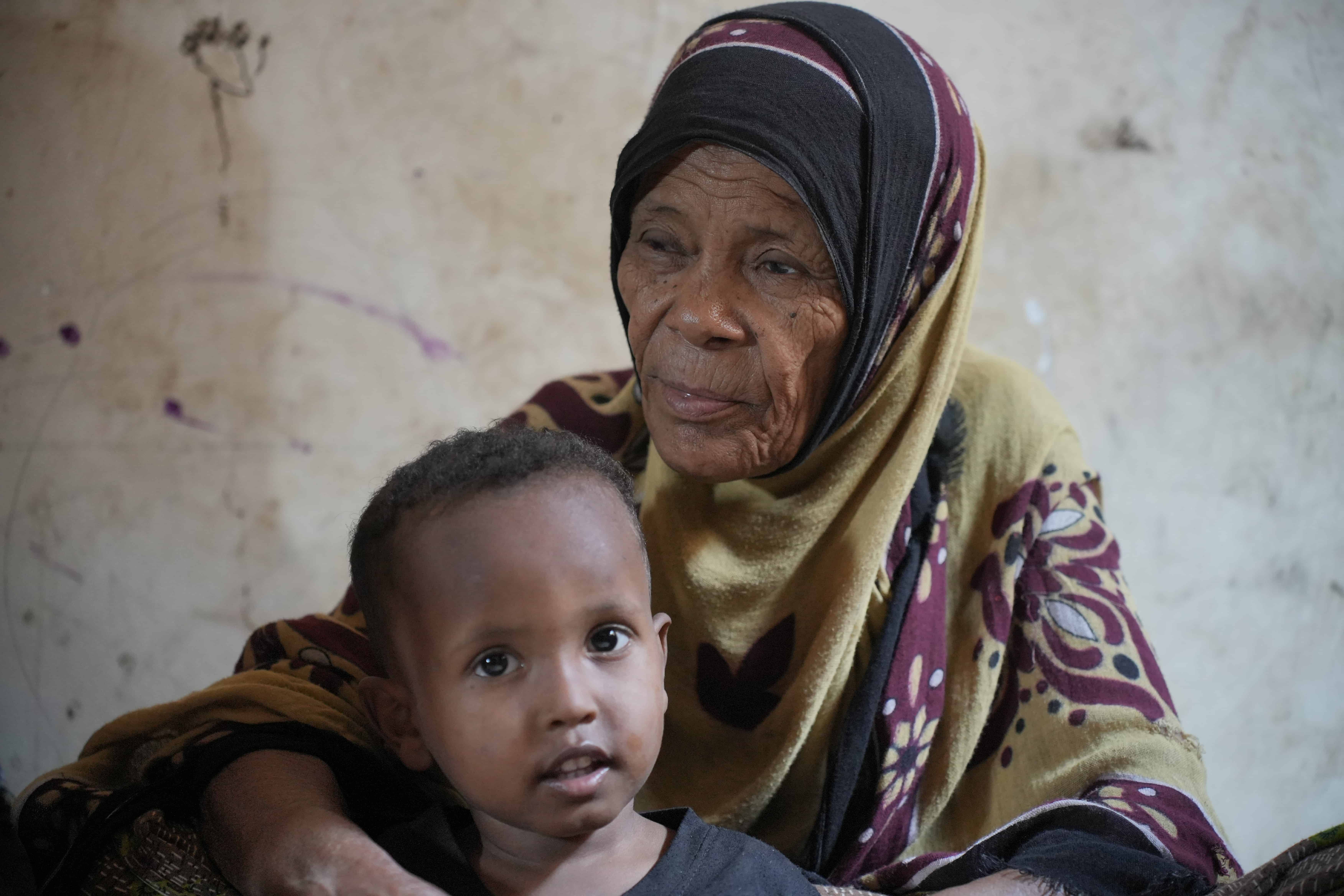 Khatema, a displaced Yemeni mother, sits with a young boy in her shelter. She is among millions of Yemenis who need humanitarian support to make ends meet.