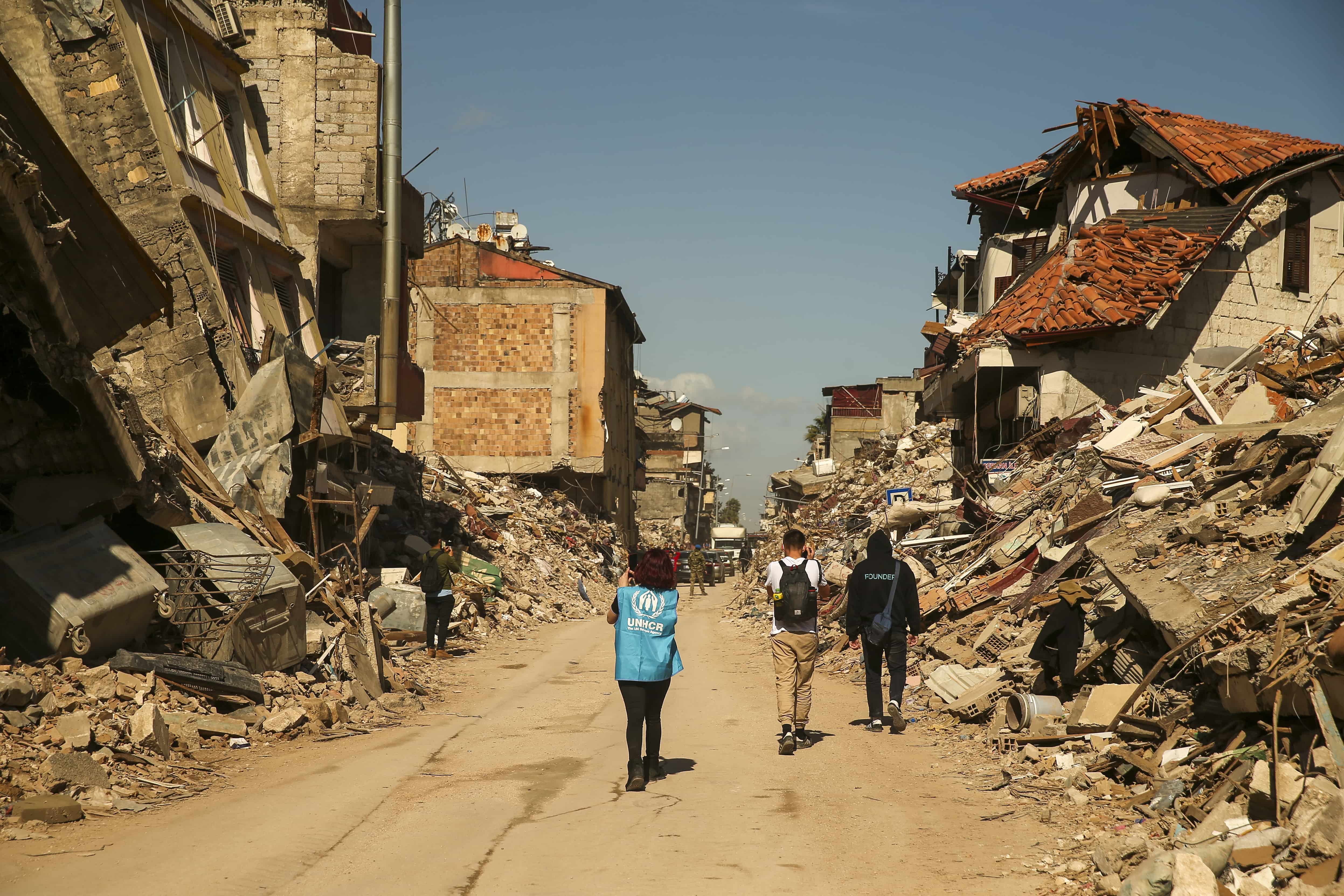 A UNHCR staff member walks amidst the devastation of the earthquakes in Hatay city.