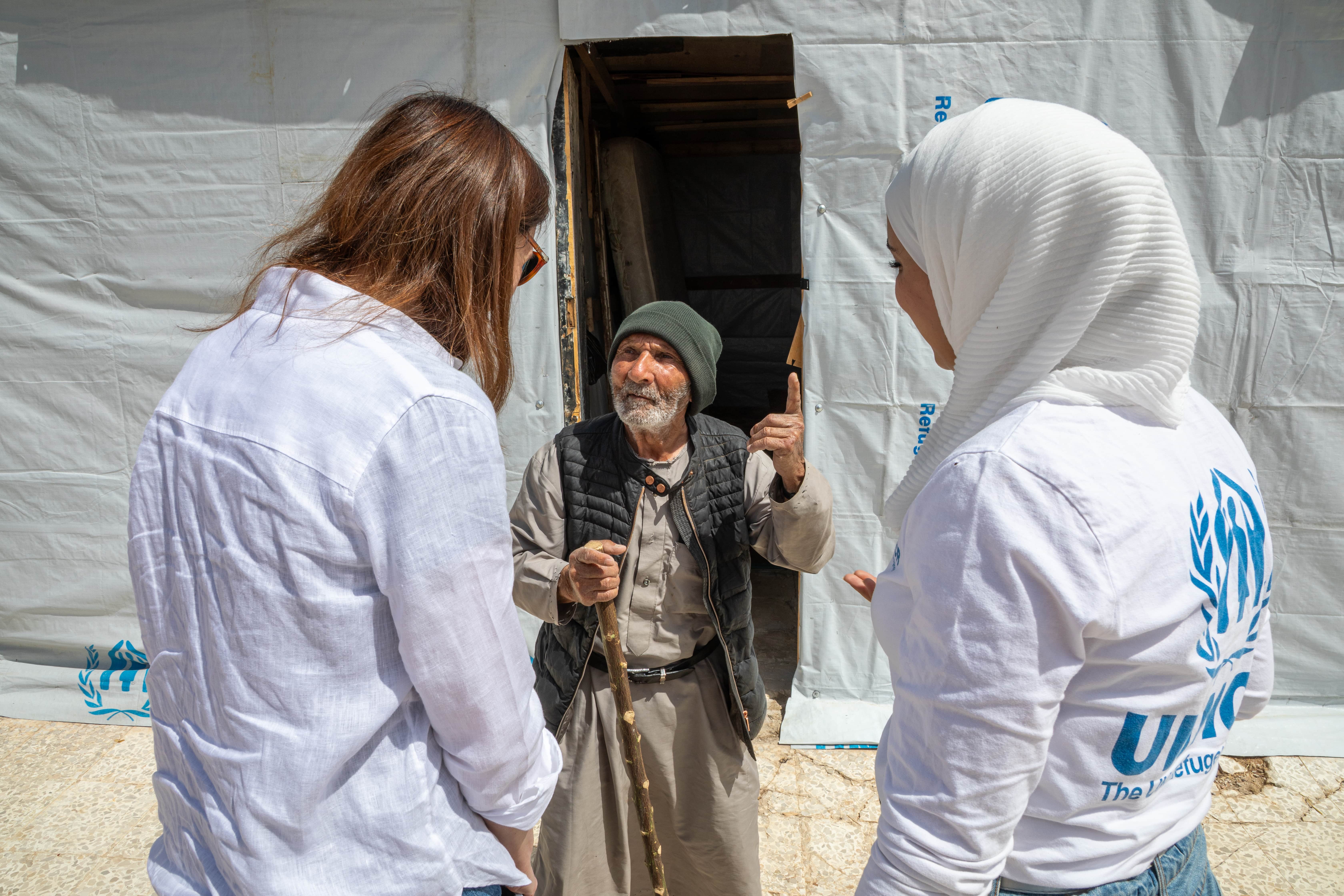 Jassim speaks with UNHCR staff members outside his shelter in Al-Qusayr, Homs governorate, Syria.