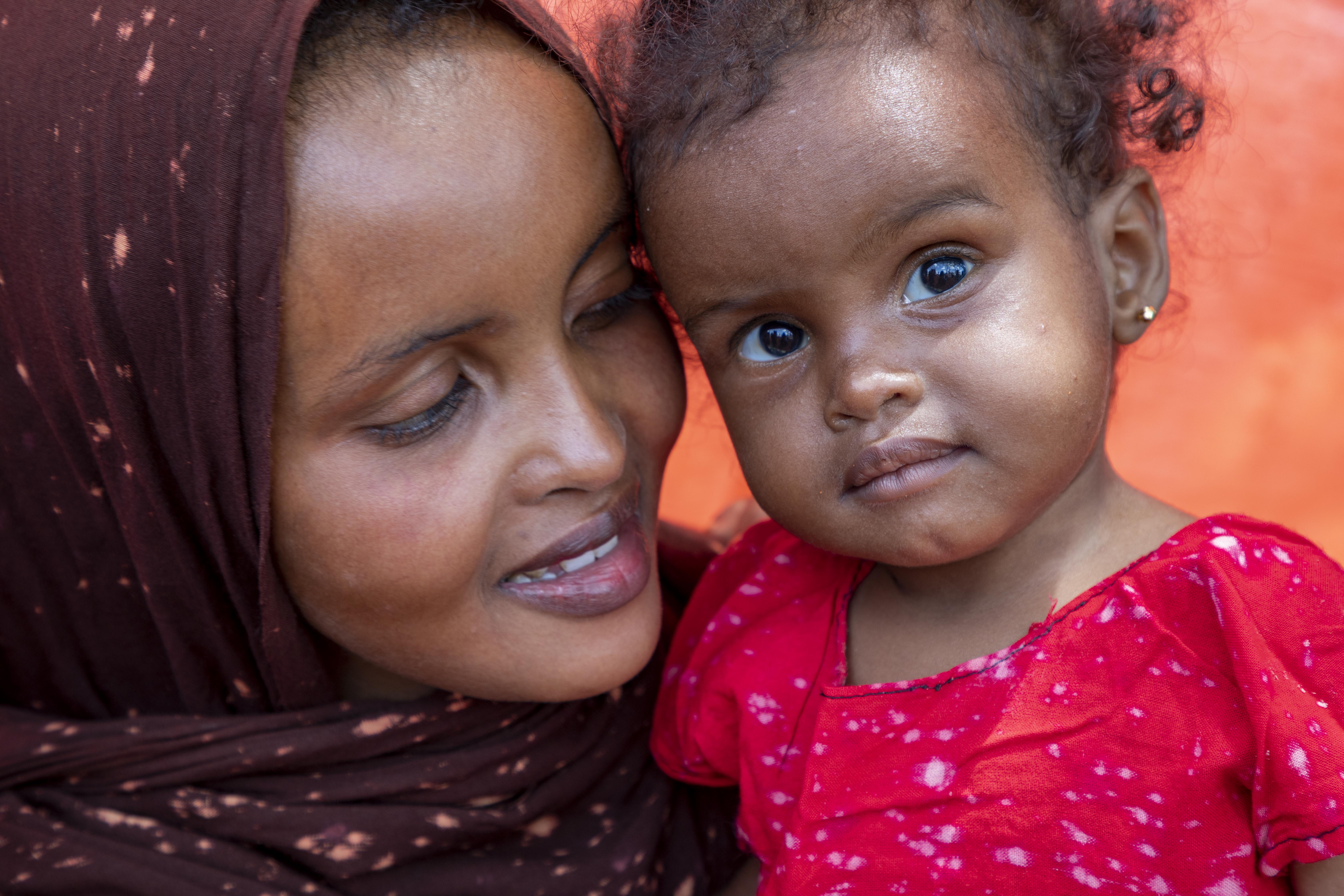 Hafsa hugs her youngest daughter Laki Cabdifatax Cali (1 year old), smiling at the camera