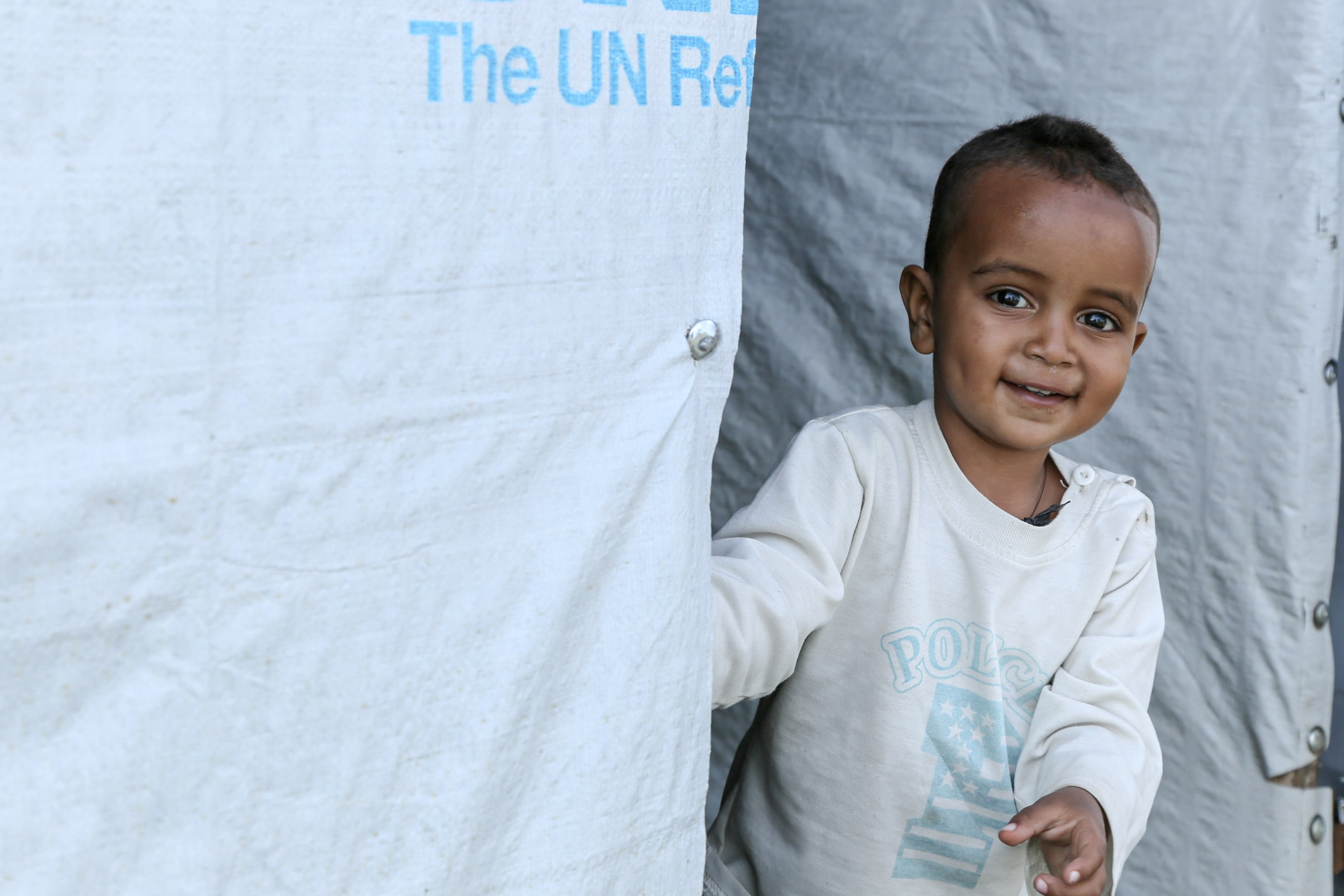 Ethipian refugee boy looks out from UNHCR tent
