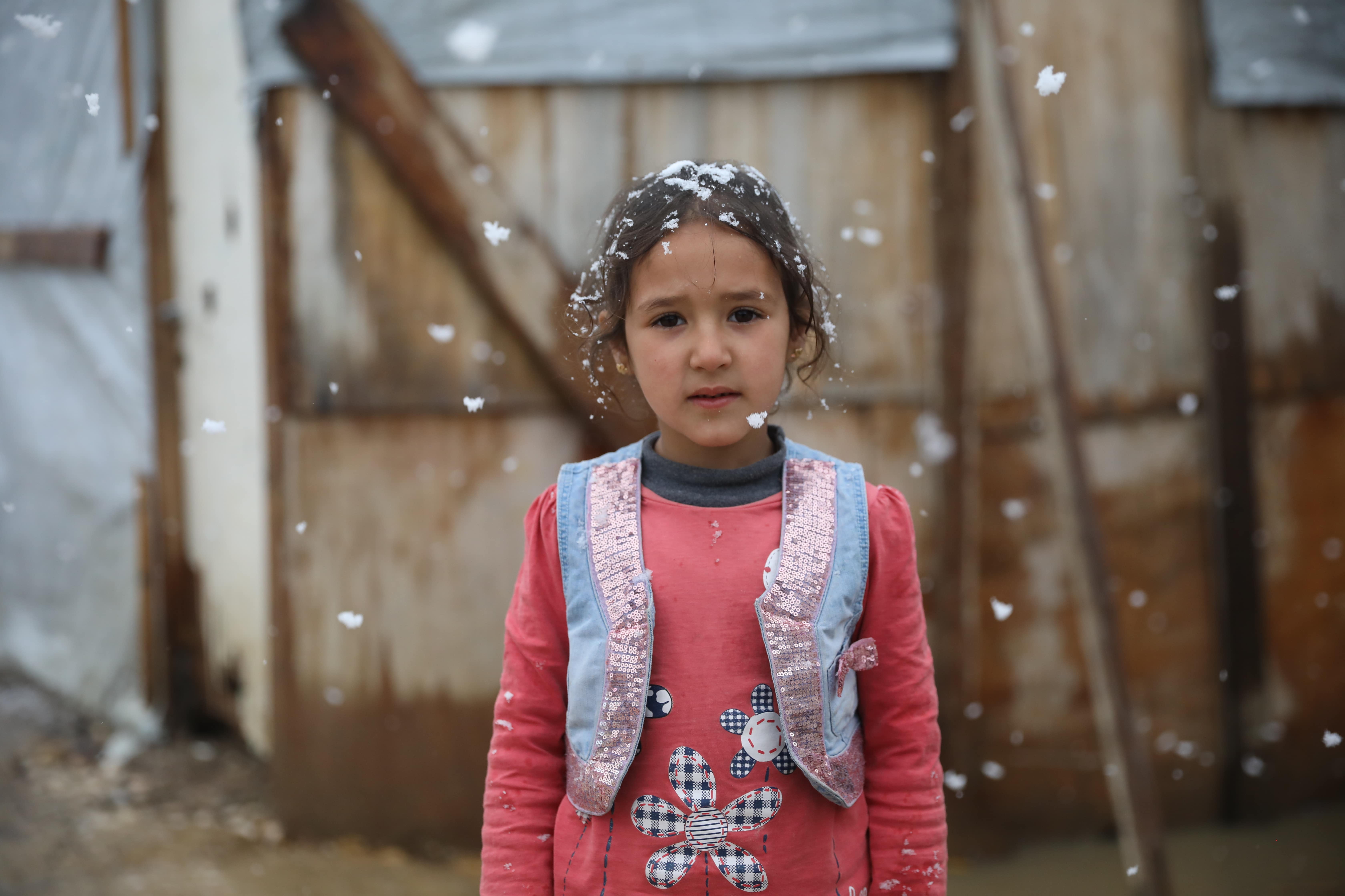  A Young girl stands in front of her tent while it snows in Beqaa valley.