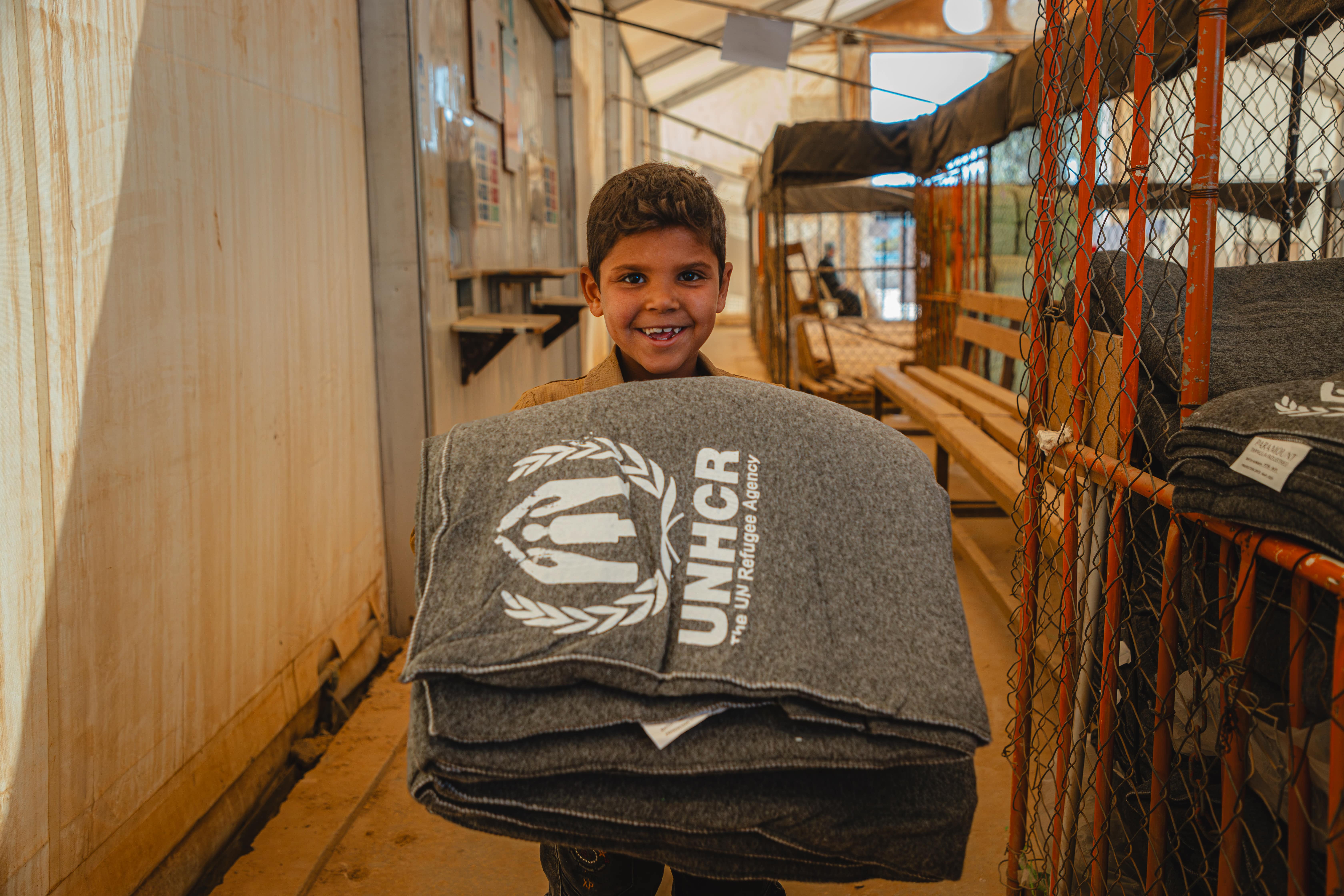 A refugee boy smiles while collecting winter blankets in Za'atari camp, Jordan