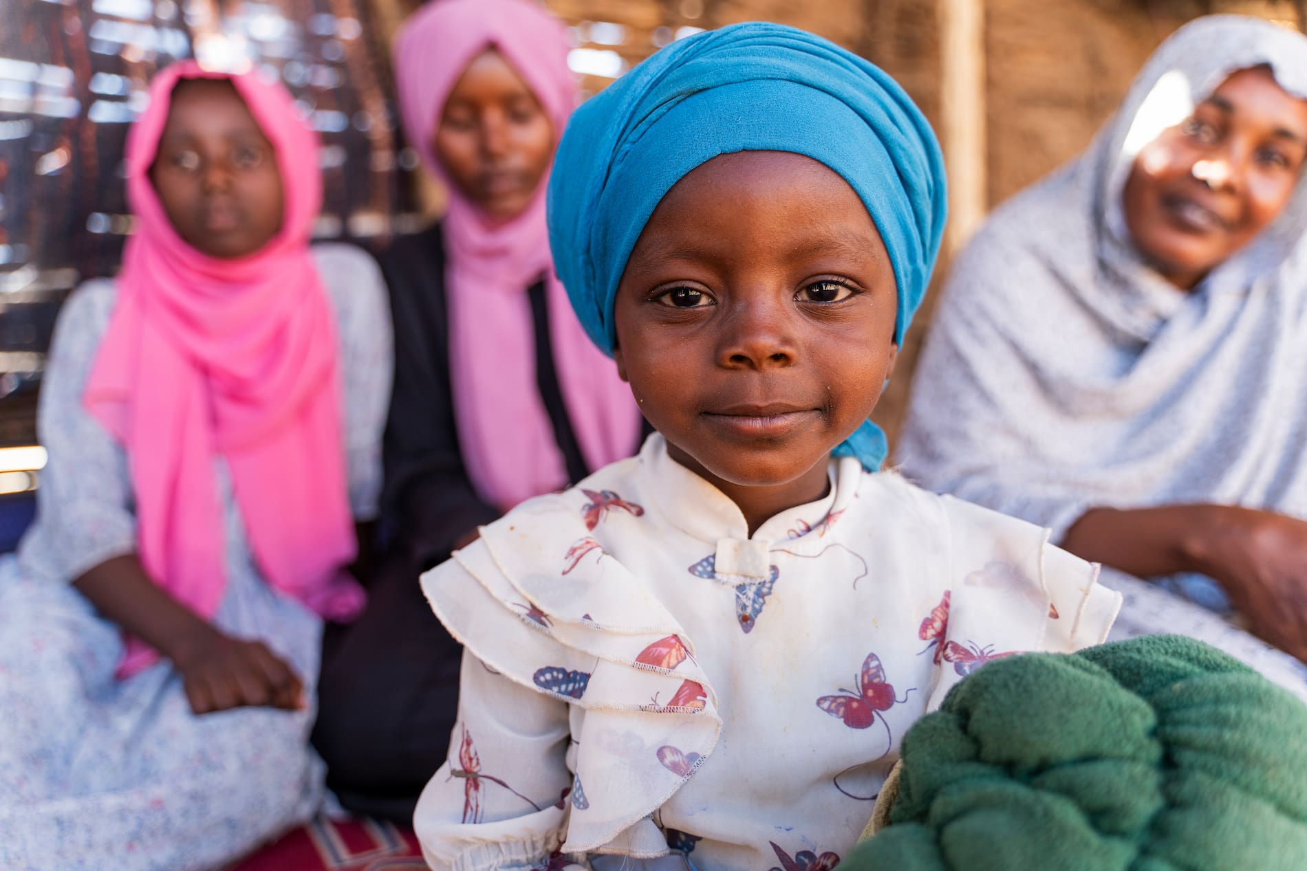Sudanese refugee Diana Adam Rajab looks at the camera with her mother and sisters in the background at the Arkoum refugee camp in eastern Chad
