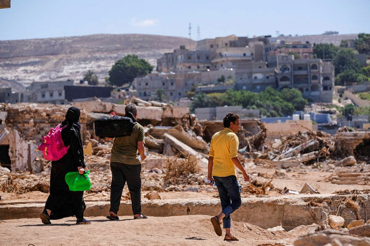 Libya. People Carrying Belongings Amidst Flood Debris