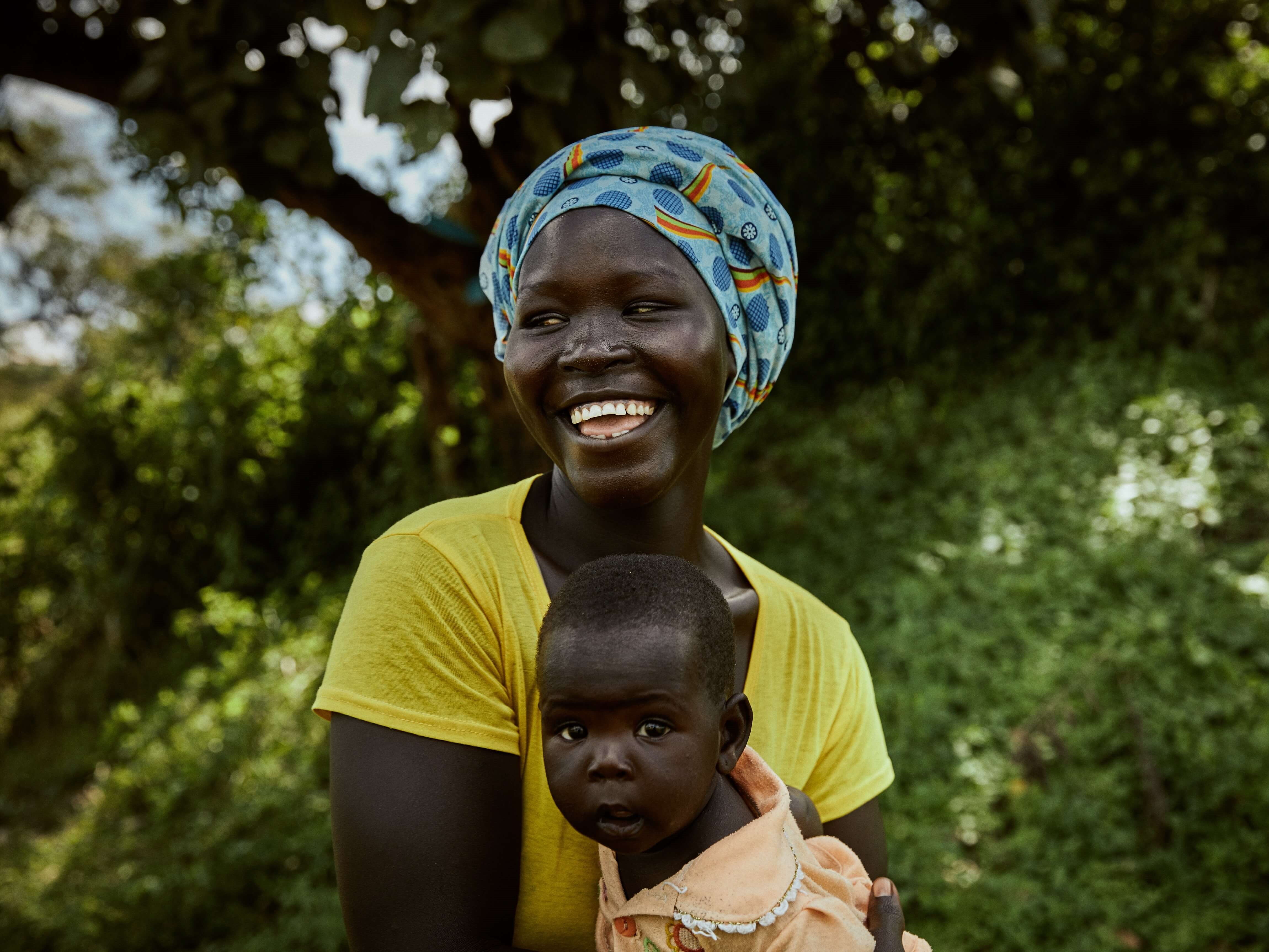 Woman laughing, holding baby. South Sudanese refugee, Bety Aredu, 22, holds her seven-month-old baby, Sarah, at Biringi settlement, Ituri province, north-east Democratic Republic of Congo, where she receives support from UNHCR. 