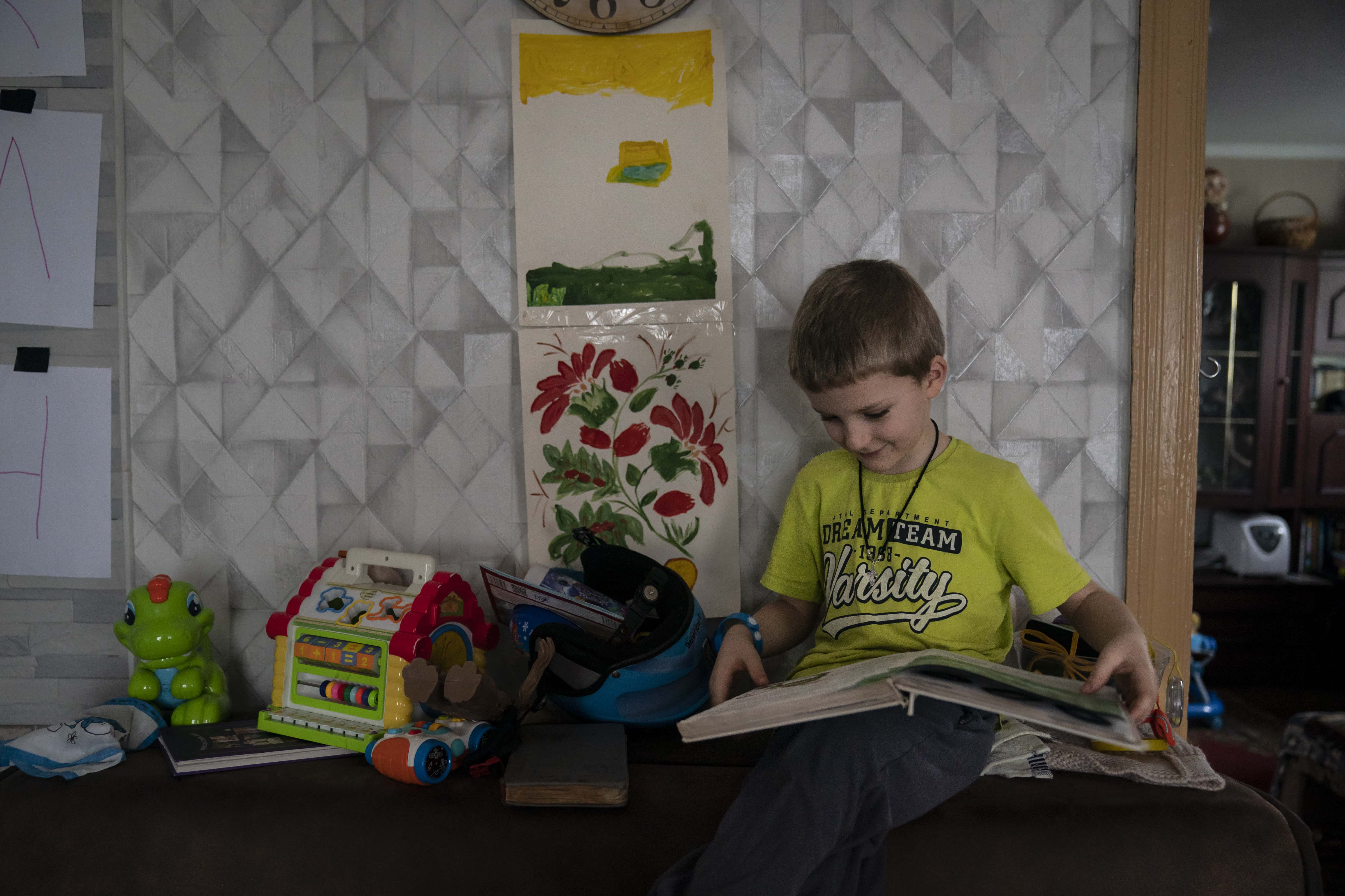Ivan reads a book in his great grandparents' home in Kyiv, Ukraine. 