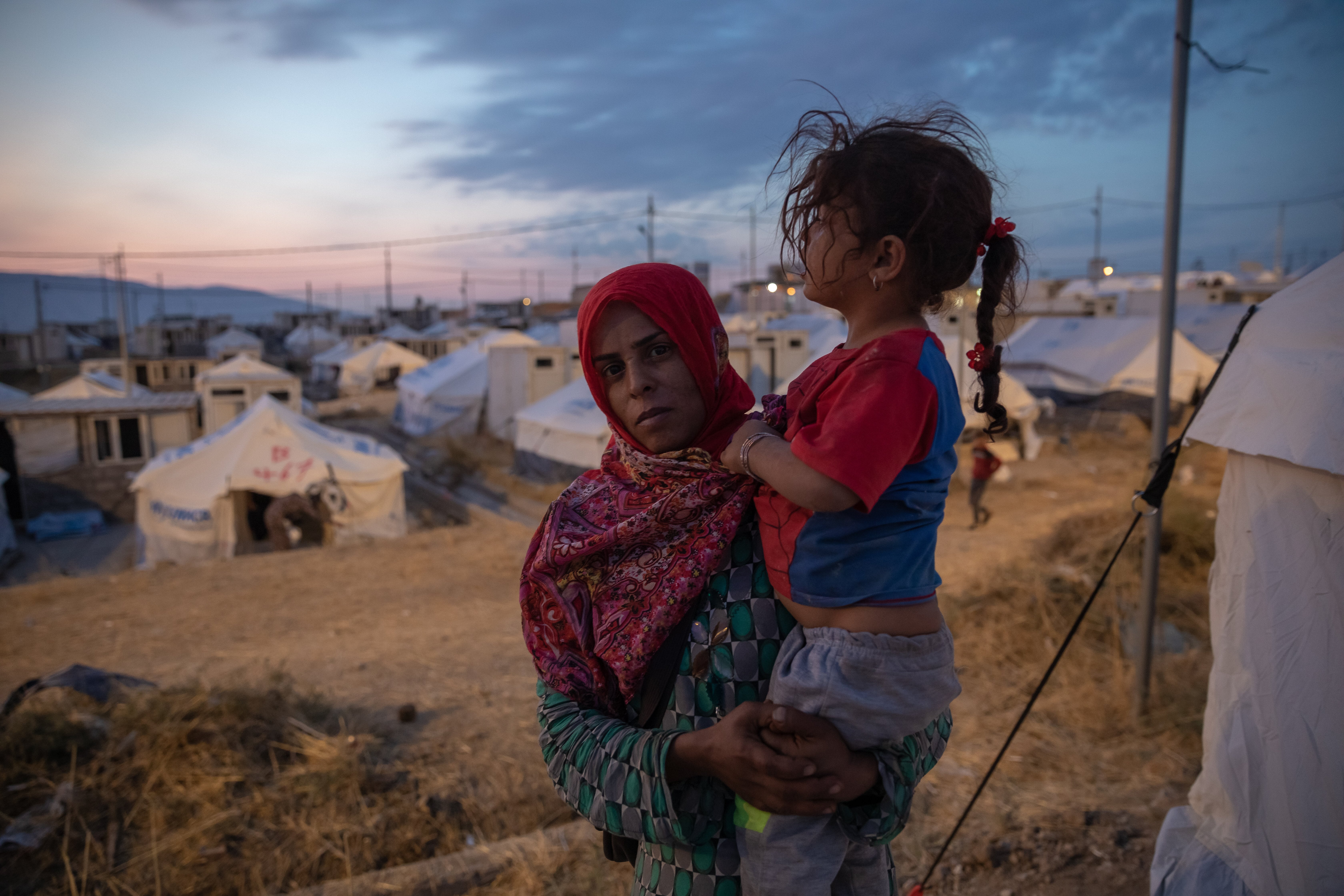 Rojin Ibrahim Davoud, a 28-year-old mother of four, holds one of her children outside a tent in Bardarash camp in Duhok, Iraq.