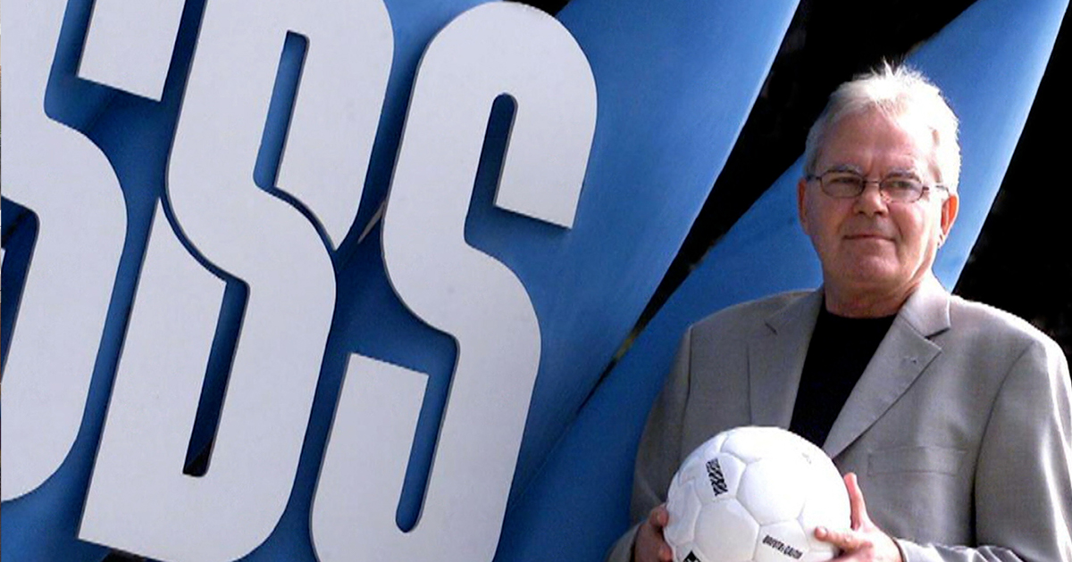 Les Murray AM holds a soccer ball in front of SBS signage © SBS