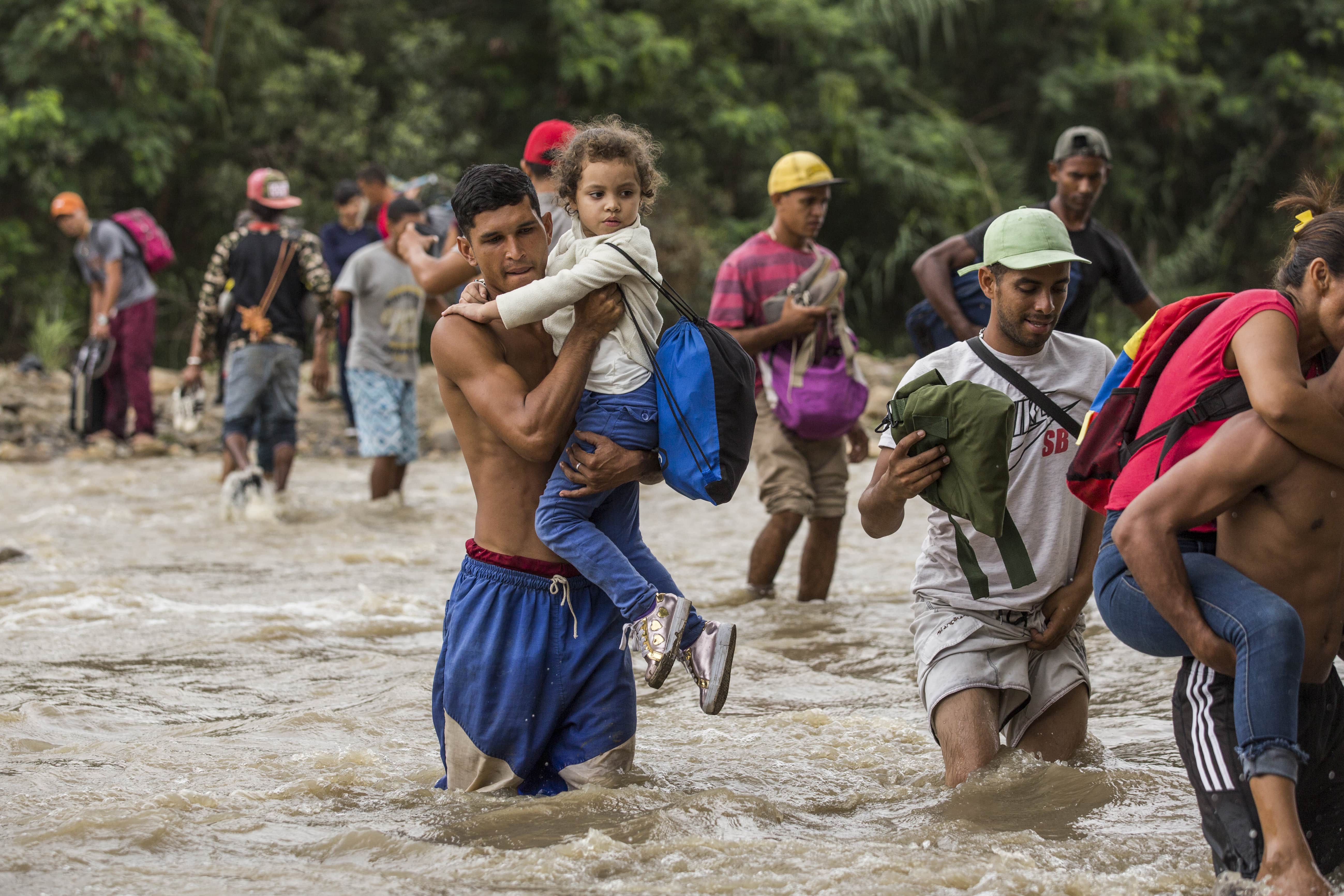 A father carries his young daughter through treacherous, muddy scrublands by the banks of the Tachira River, which forms the border between Venezuela and Colombia. In a context of rampant hyperinflation, food shortages, political turmoil, violence and persecution, more than 3 million Venezuelans have fled the country, making such perilous journeys in search of safety. 