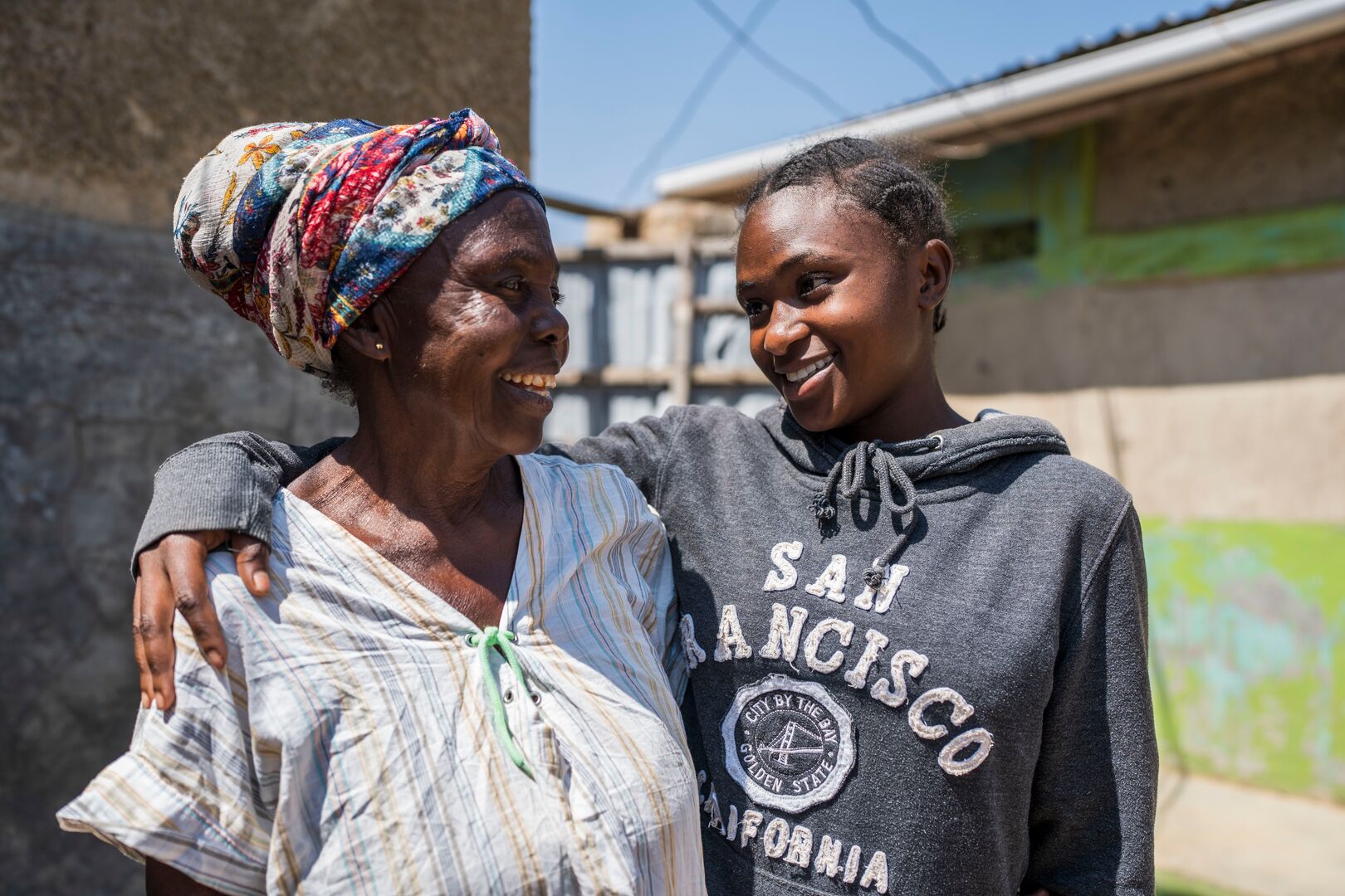 Omwali* and her grandmother Nia* outside their home in Nakivale refugee settlement.