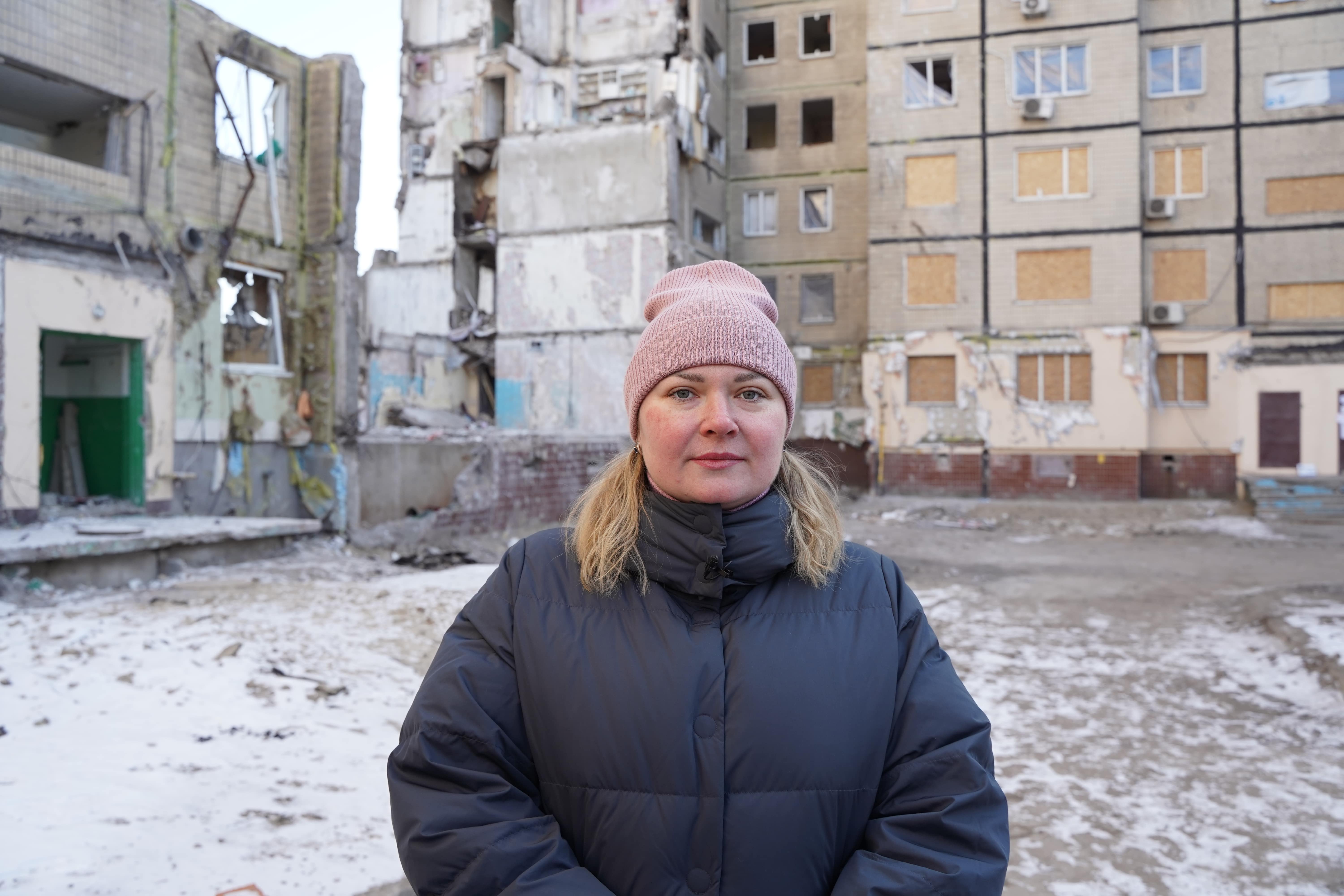 Anastasiya stands in front of her destroyed apartment building. 