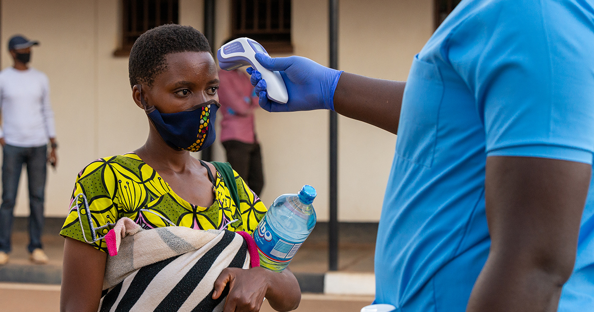 A Burundian refugee at Mahama camp has her temperature taken for signs of COVID-19 symptoms, as UNHCR staff facilitate the voluntary return from Rwanda. @UNHCR/Eugene Sibomana