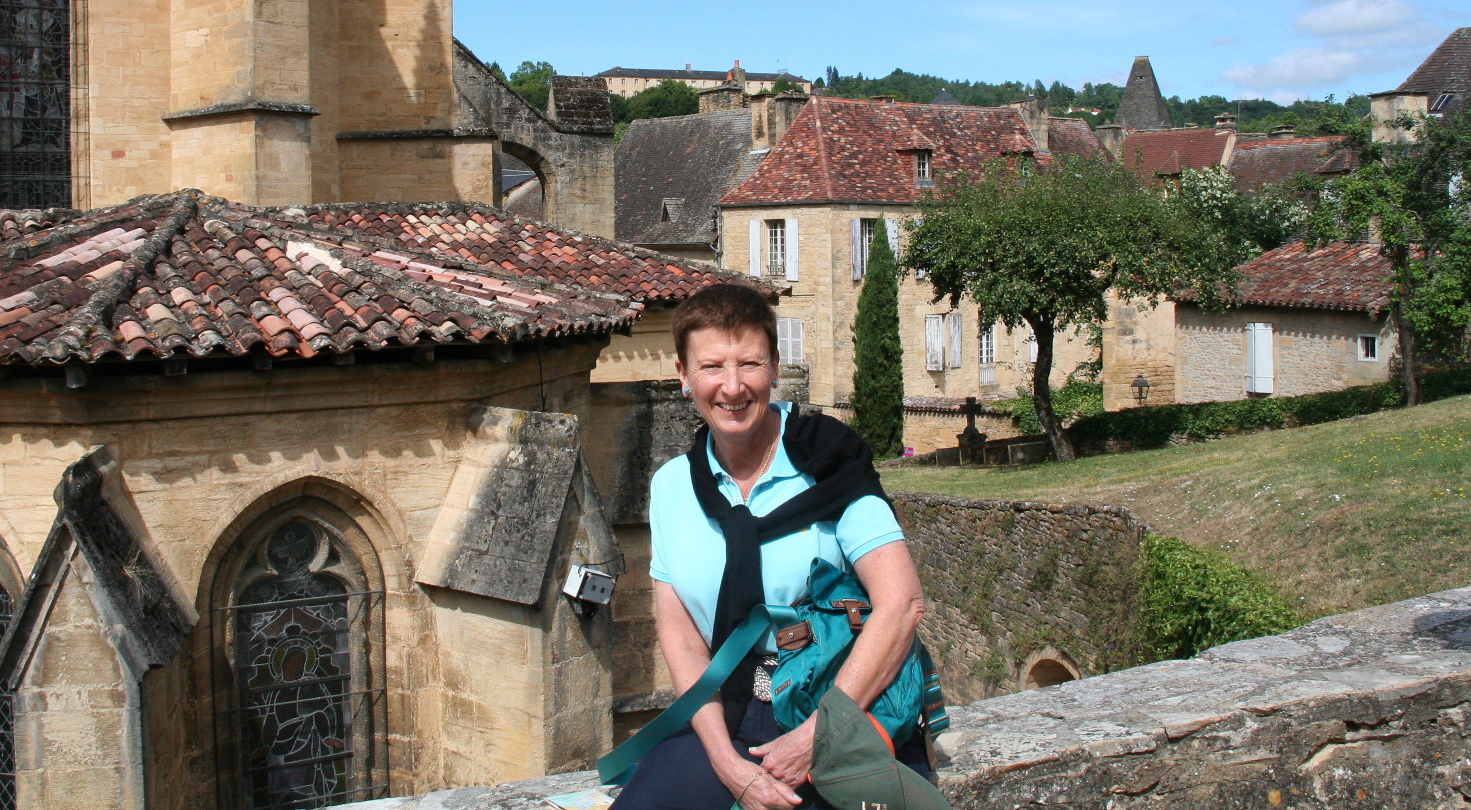 Australia for UNHCR bequestor Stephanie sits smiling on an old stone wall