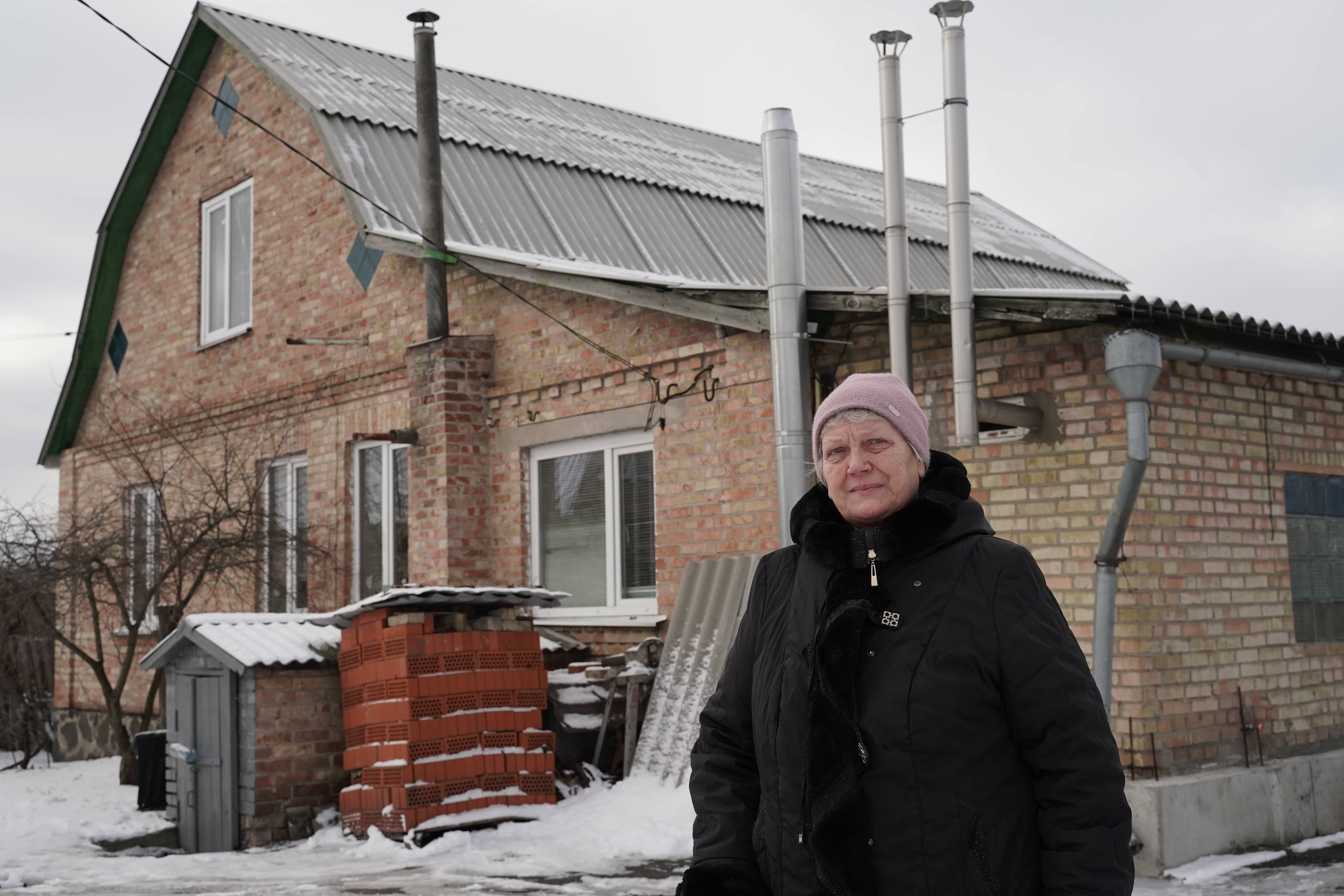 Lidiia, 69, stands in front of her home in Horenka Village, Kyiv Oblast, Ukraine.
